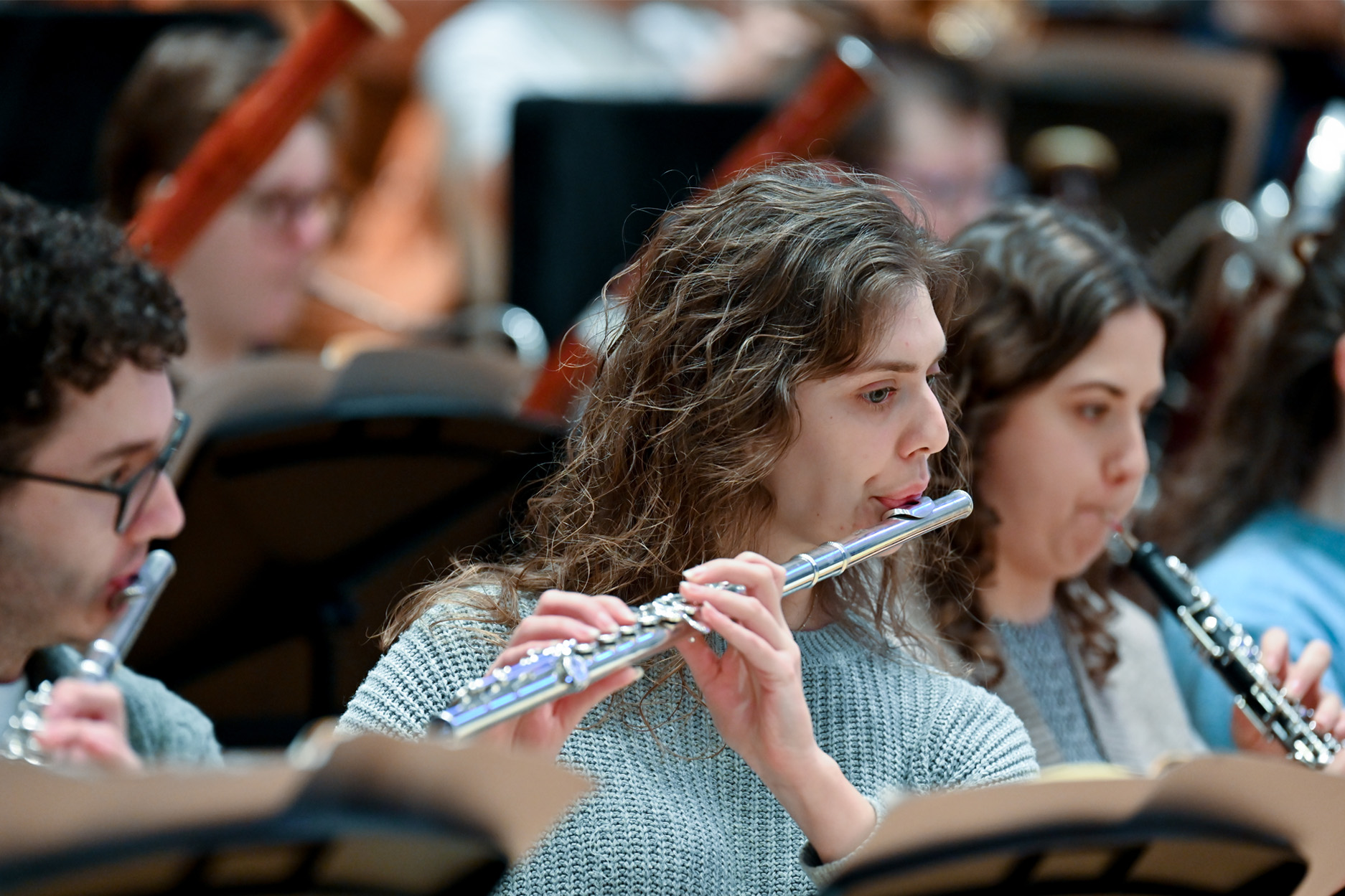 A female flautist playing in an orchestral rehearsal